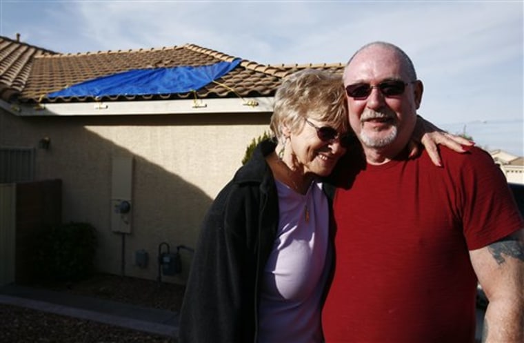 Penny and Bill White stand in front of their house in Henderson, Nev., on Tuesday. Earlier in the day, a chunk of ice fell from an airplane and landed on their roof, creating a hole about the size of a sofa cushion.